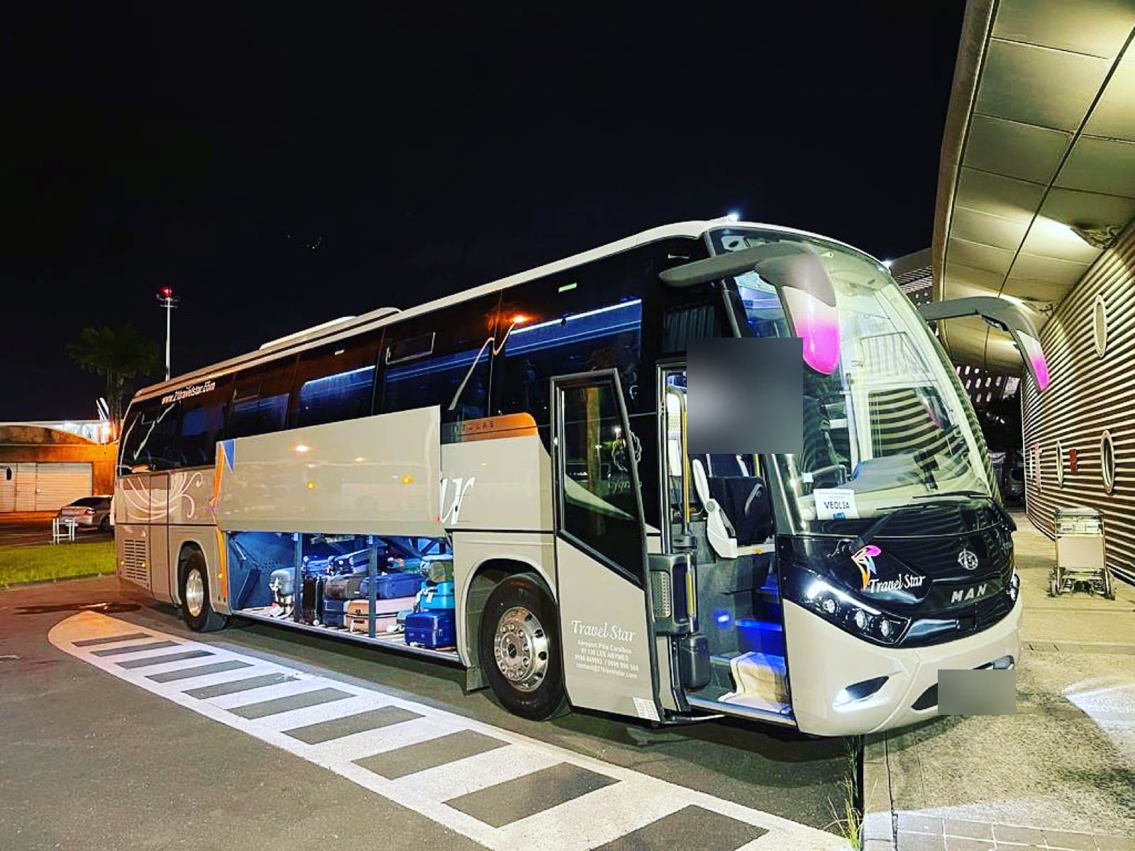 Touring coach from the Travel Star fleet, at Pôle Caraïbes airport at night.